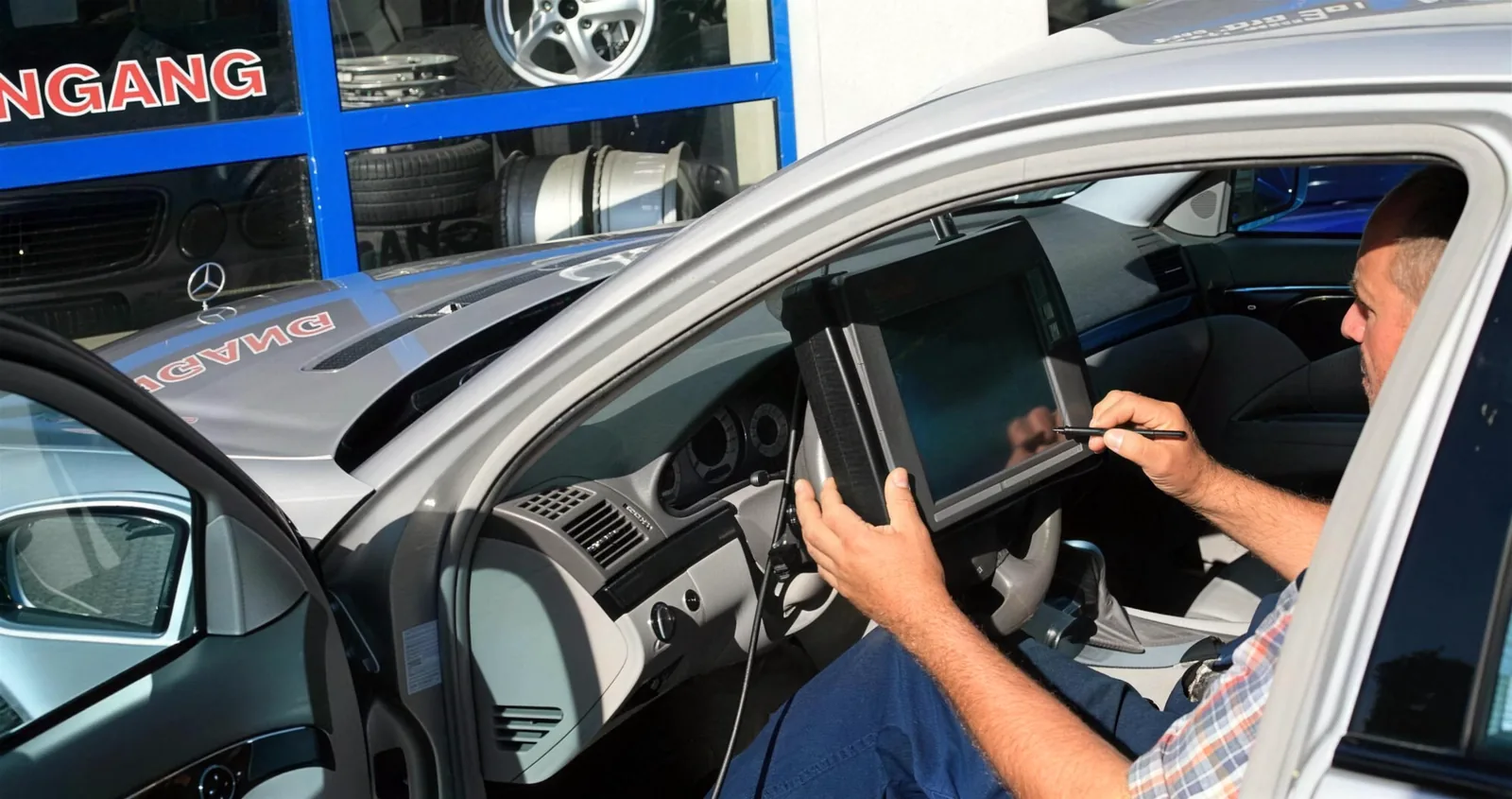 Mann mit dem Diagnosegerät im Fahrzeug